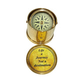 A gold-colored brass gimbal compass with an engraved inscription 'Life is a Journey Not a Destination' on the cover of its case.